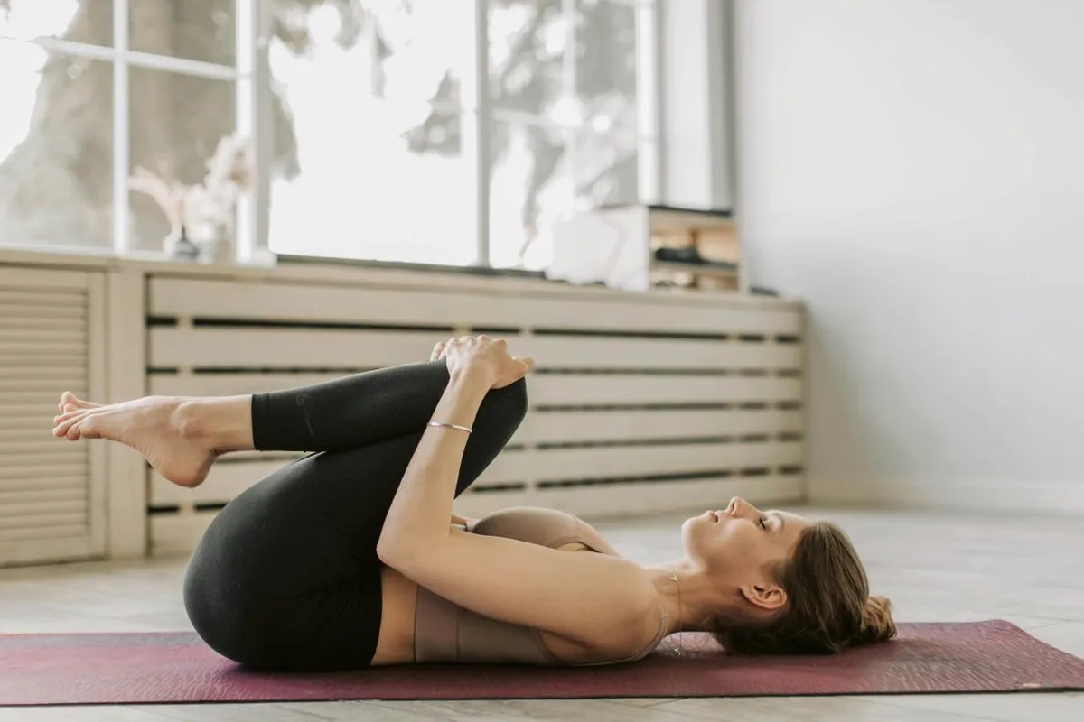 Person holding a core-strengthening yoga pose on a mat